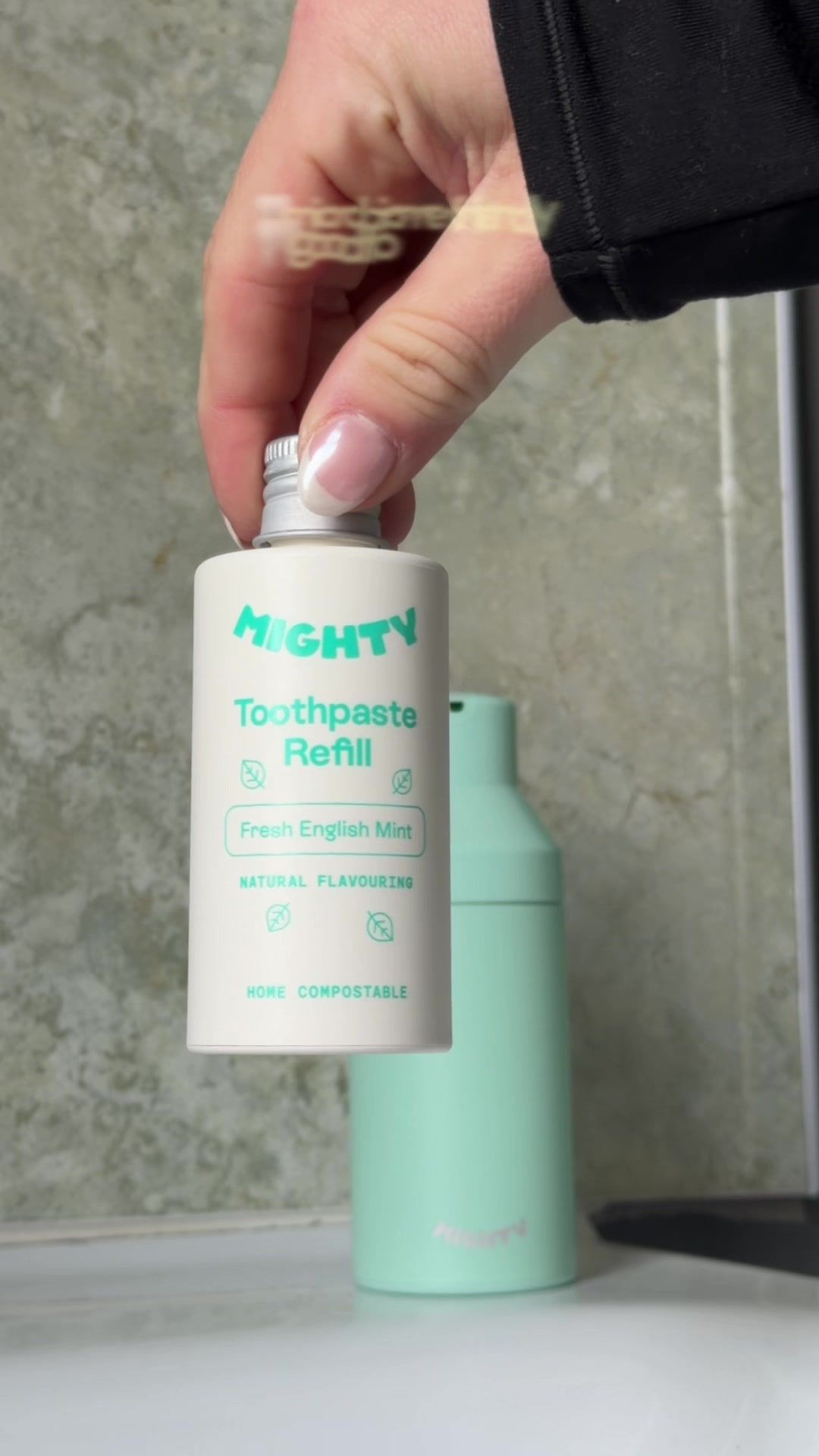 A Mighty toothpaste refill held beside its refillable dispenser.