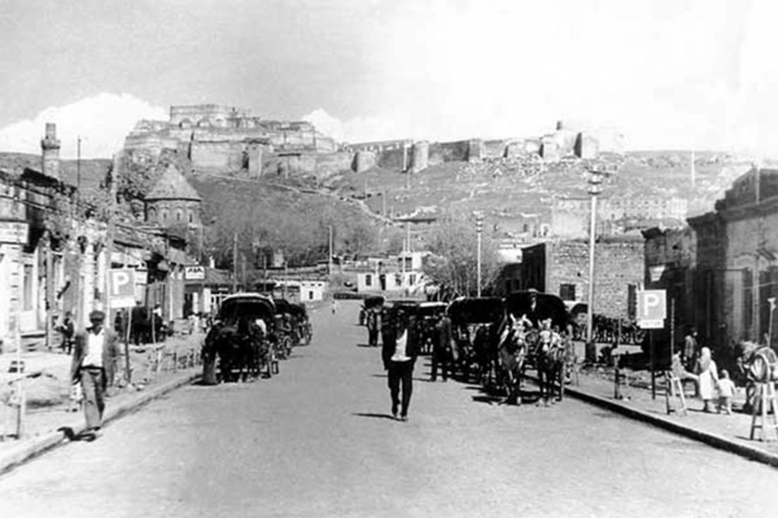 Kars'taki tarihi cadde, at arabaları ve kalenin manzarası, siyah beyaz fotoğraf.