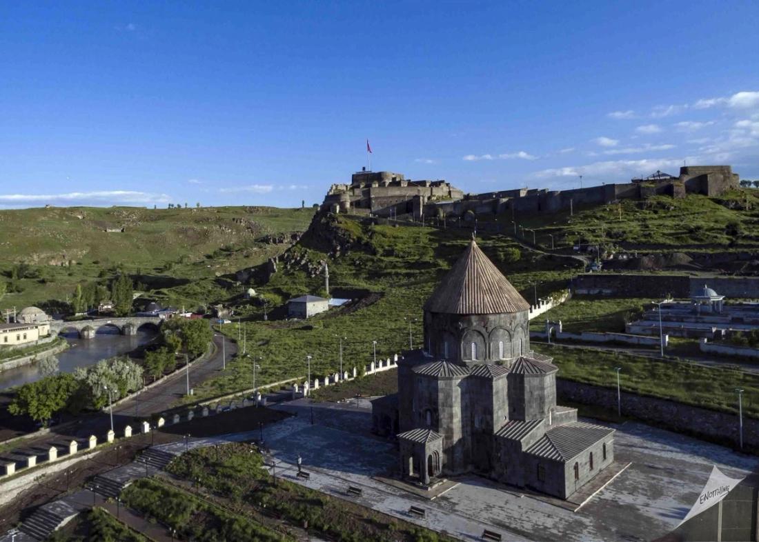 Kars'taki tarihi Harakānî Külliyesi ve çevresi, yeşil alanlar ve kale, gün batımı.