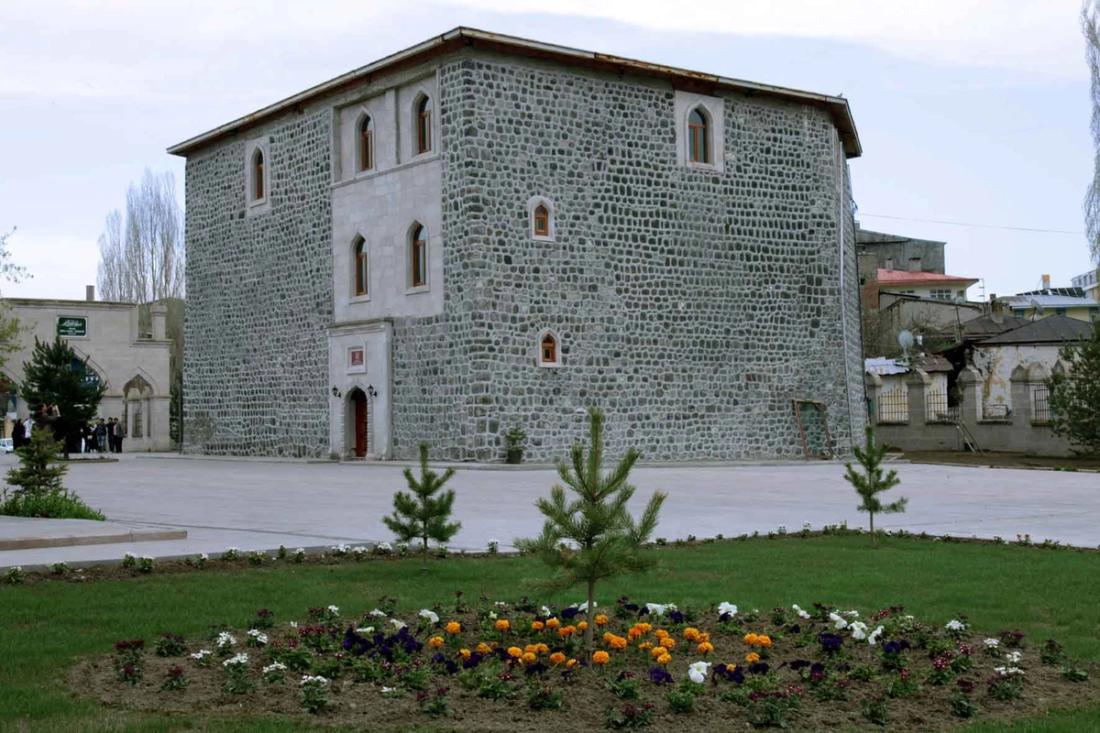 Taş bina, çiçekler ve gökyüzü. Uluslararası Harakani Kültür Vakfı binası önünde.