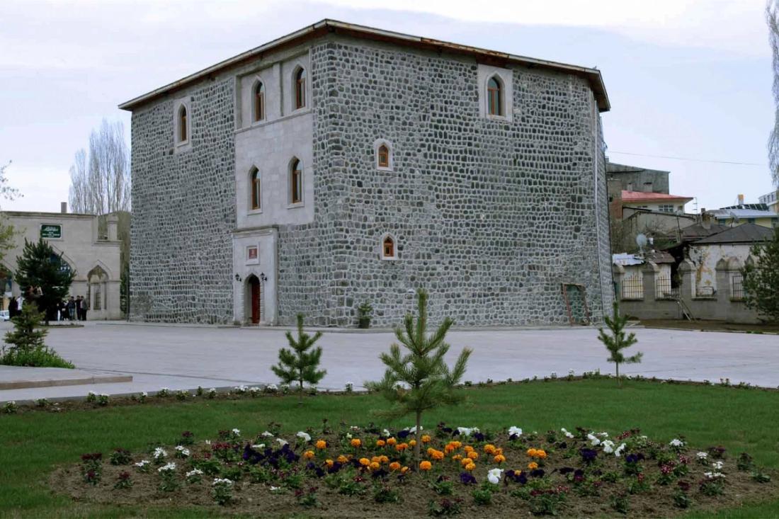 Taş bina, çiçekli bahçe ve ağaçlarla dolu bir alan, Harakānî Külliyesi, Uluslararası Harakani Kültür Vakfı.