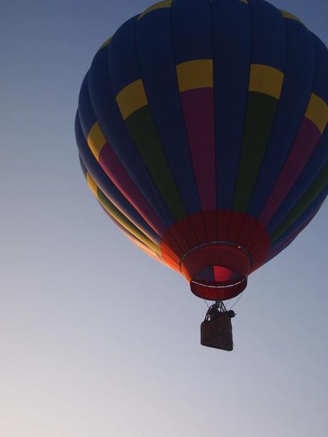 Hot air balloon in light blue cloud-free sky.