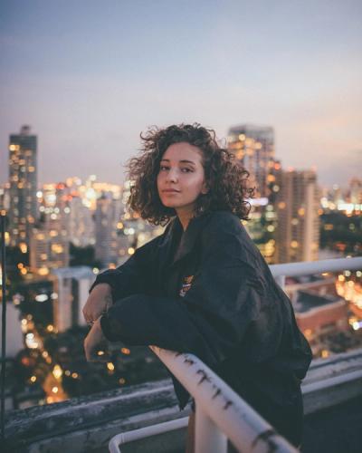 Mujer en un balcón con edificios detrás, siendo fotografiada