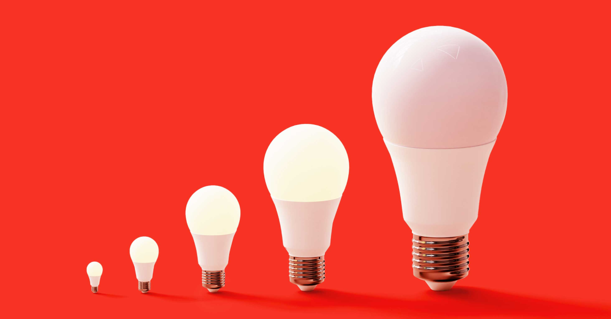 A row of five light bulbs that are all different sizes on a red background. The fifth and biggest light bulb is not lit up. 