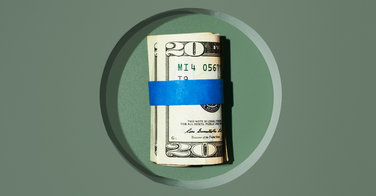 A rolled up $20 bill with blue tape around it on a green background. 