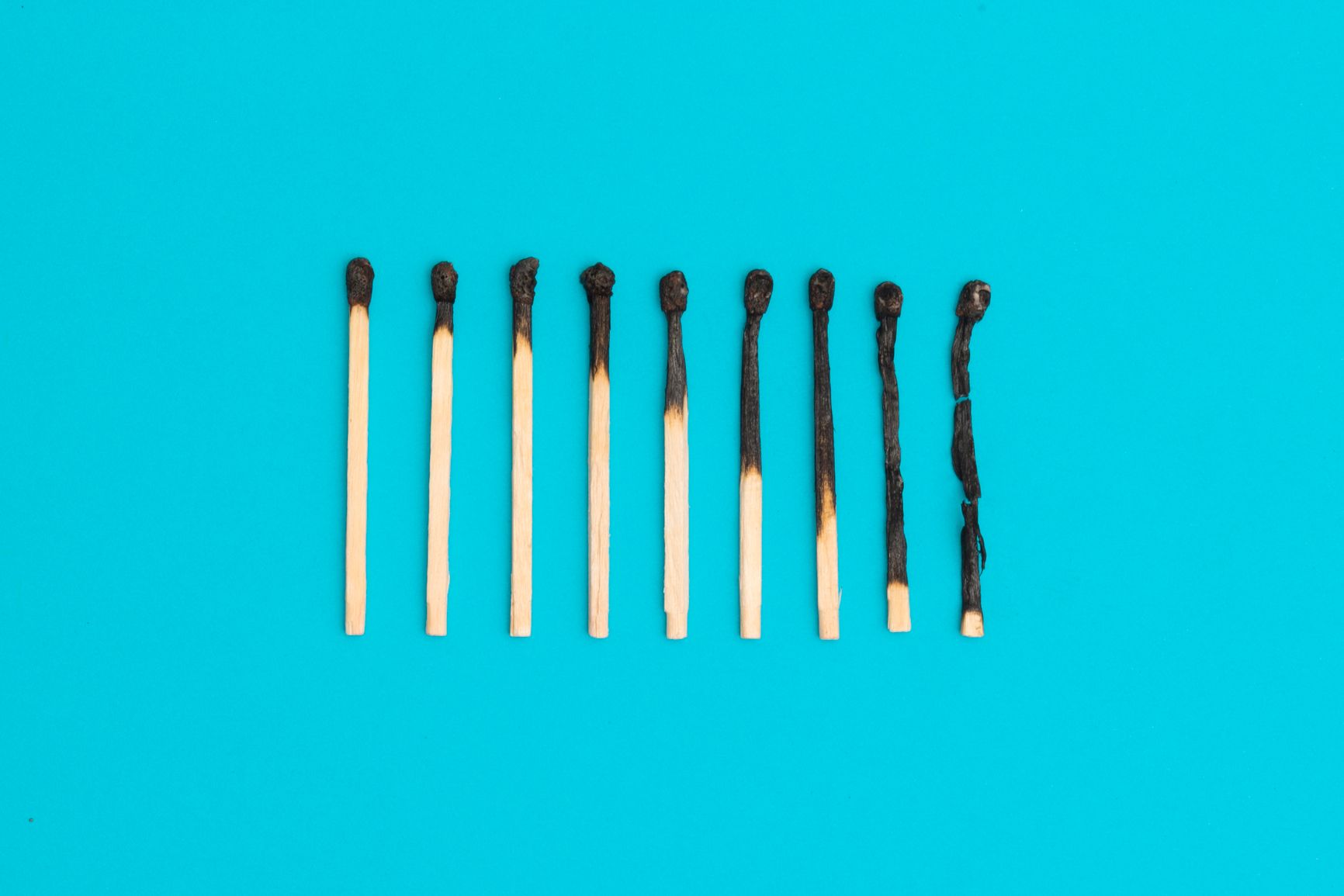 Nine burnt matches against a blue background. 