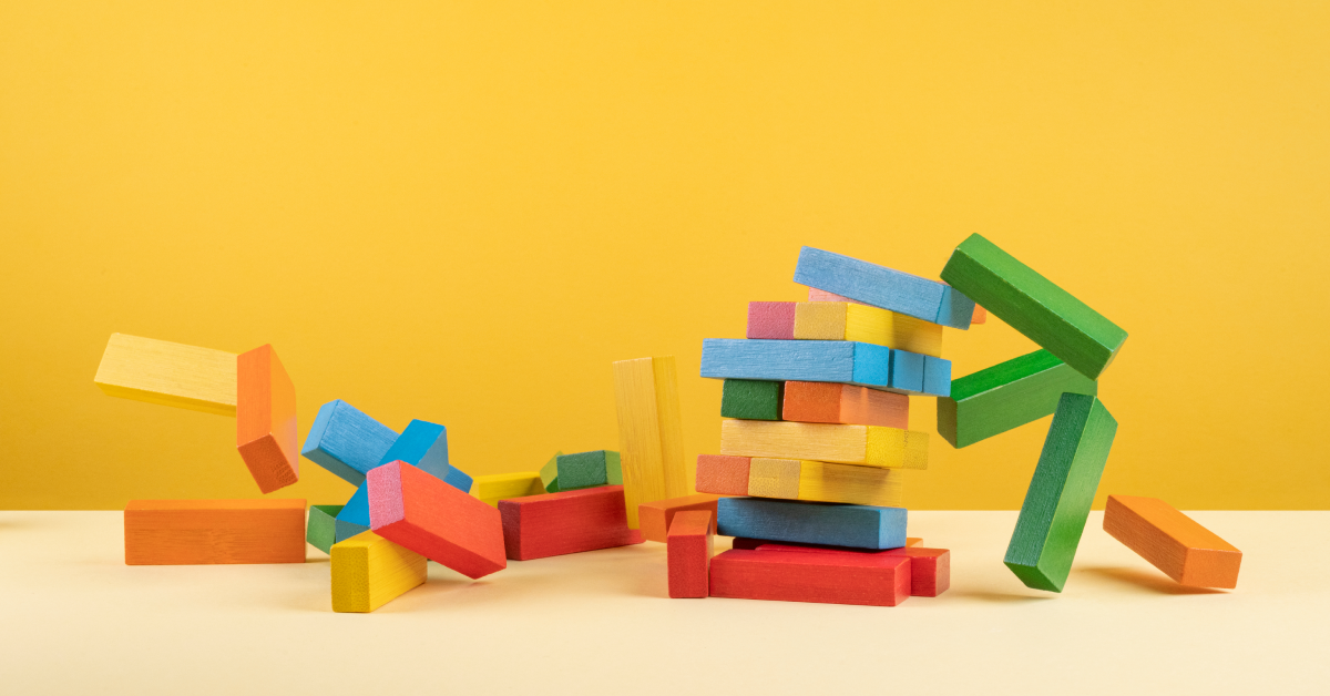 A stack of colorful kid blocks falling against a yellow background. 