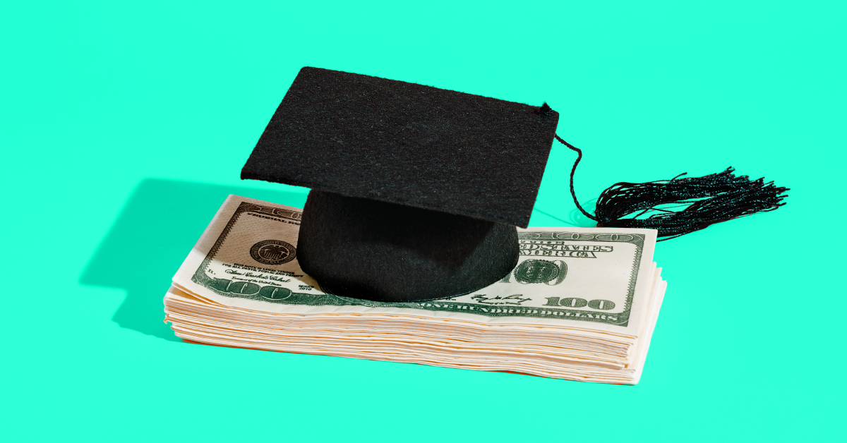 A black graduation cap on a stack of money with a blue background. 