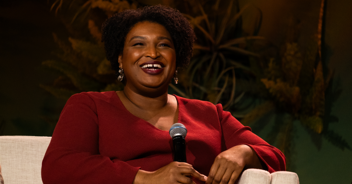 An image of Stacey Abrams smiling with a red sweater on.