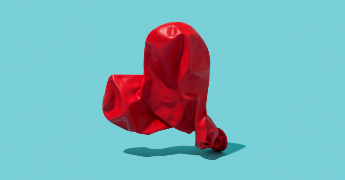 A red deflated heart-shaped balloon on a sky blue background. 