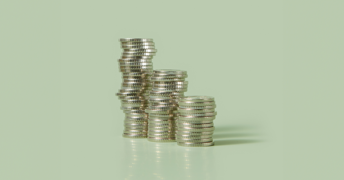 A stack of coins on a mint green background. 