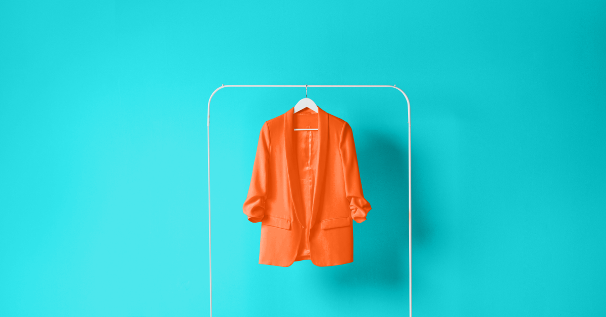 An orange blazer on a clothes hanger against a baby blue background. 