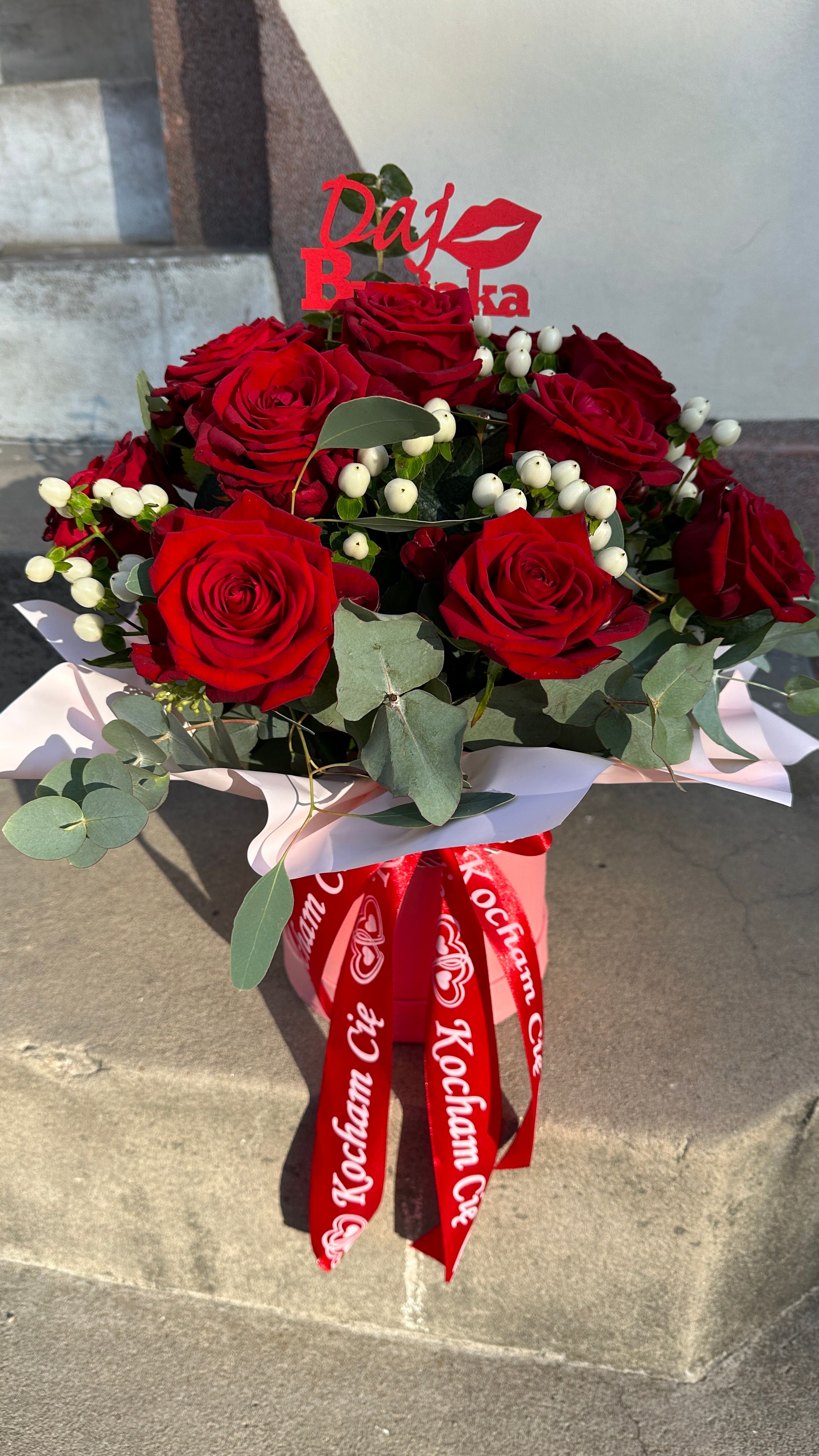 Flowerbox z czerwonej róży, eukaliptusa i białego hypericum wyróżnia się wyrazistym połączeniem czerwieni, bieli i zieleni.