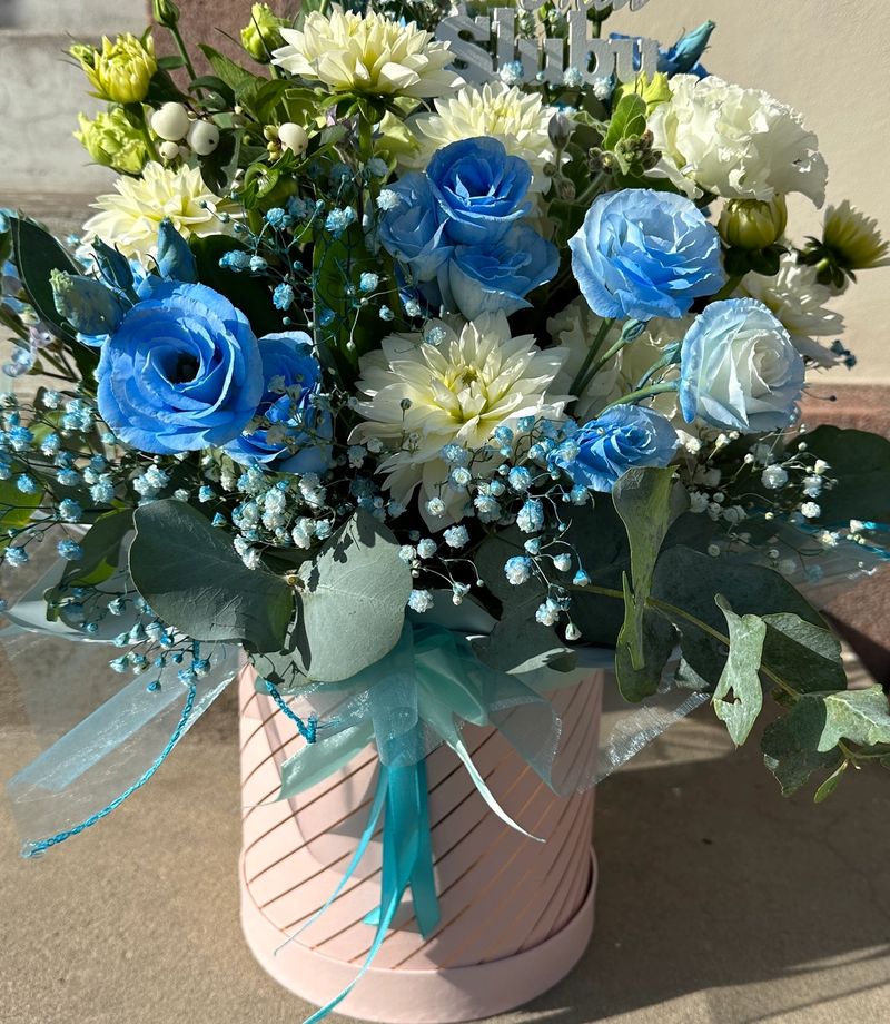 Delikatny flowerbox z niebieską eustomą oraz różnorodnymi kwiatami w kremowych odcieniach to subtelna kompozycja o eleganckim i świeżym charakterze.