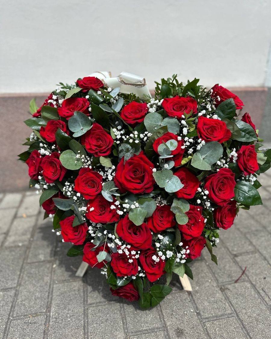 Wieniec pogrzebowy w kształcie serca, wykonany z czerwonej róży, delikatnej gipsówki oraz eukaliptusa.