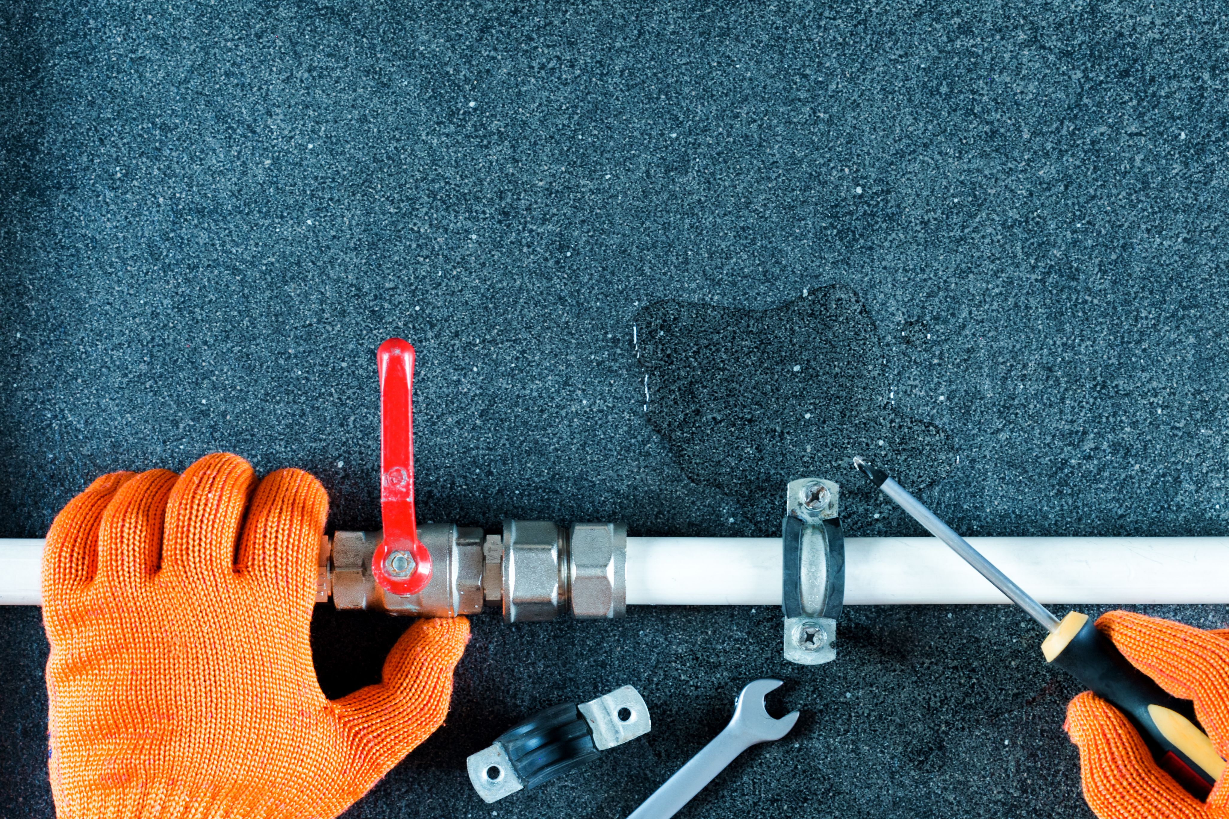 Miehen kädet tekemässä putkiremonttia