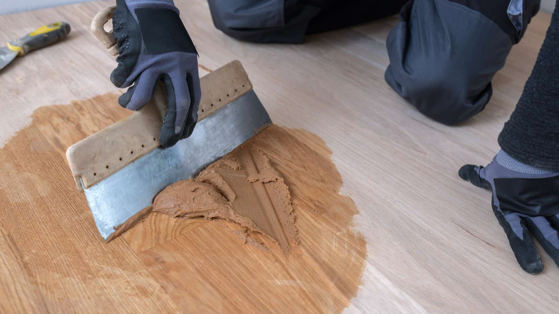Parketti on asennettu ja urakoitsija käsittelee parkettilattian pintaa