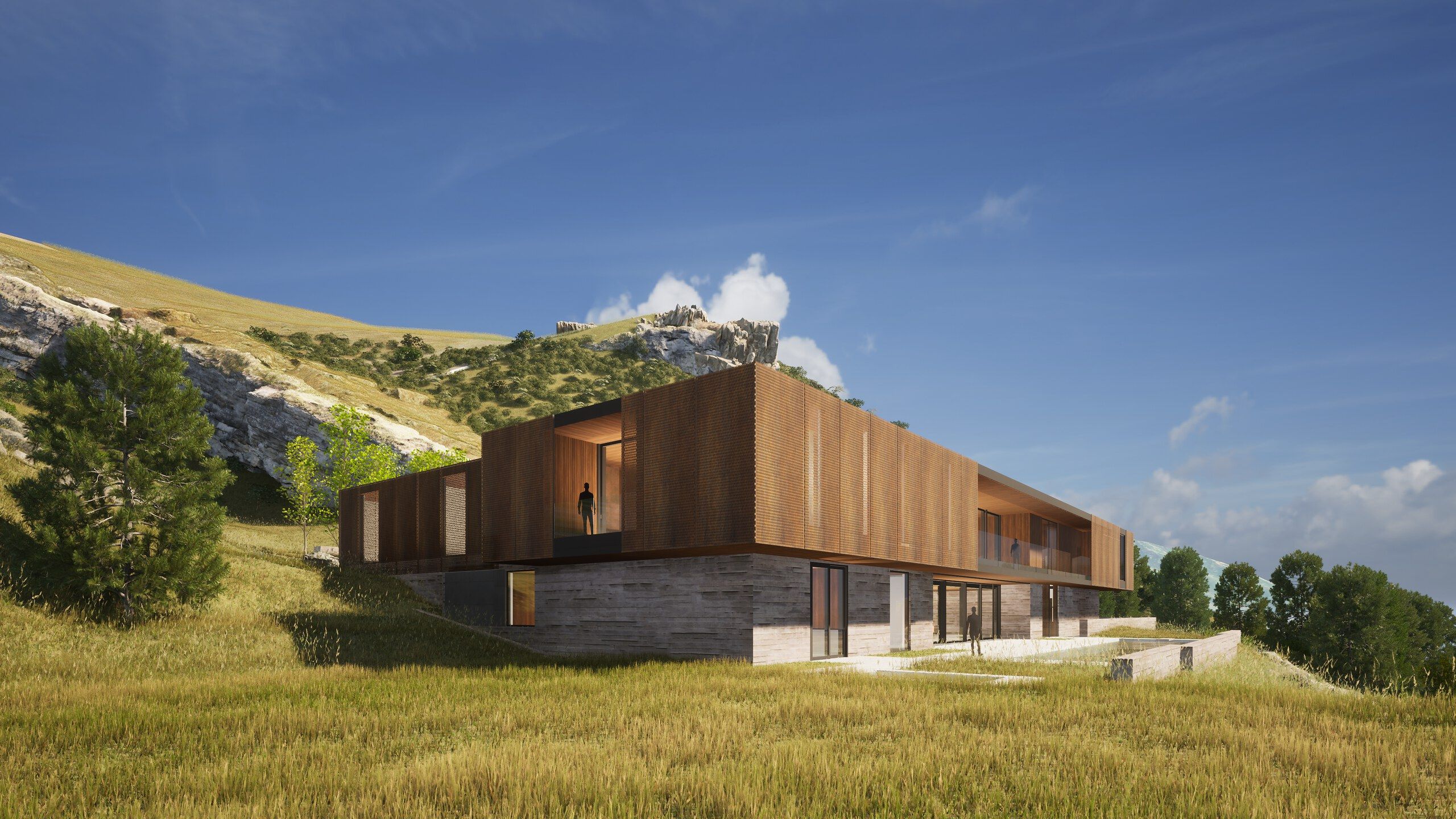 Contemporary hillside home with a perforated wooden upper facade and a concrete lower level, featuring large glass panels and a balcony with a person, nestled in a golden grassy landscape under a clear blue sky.
