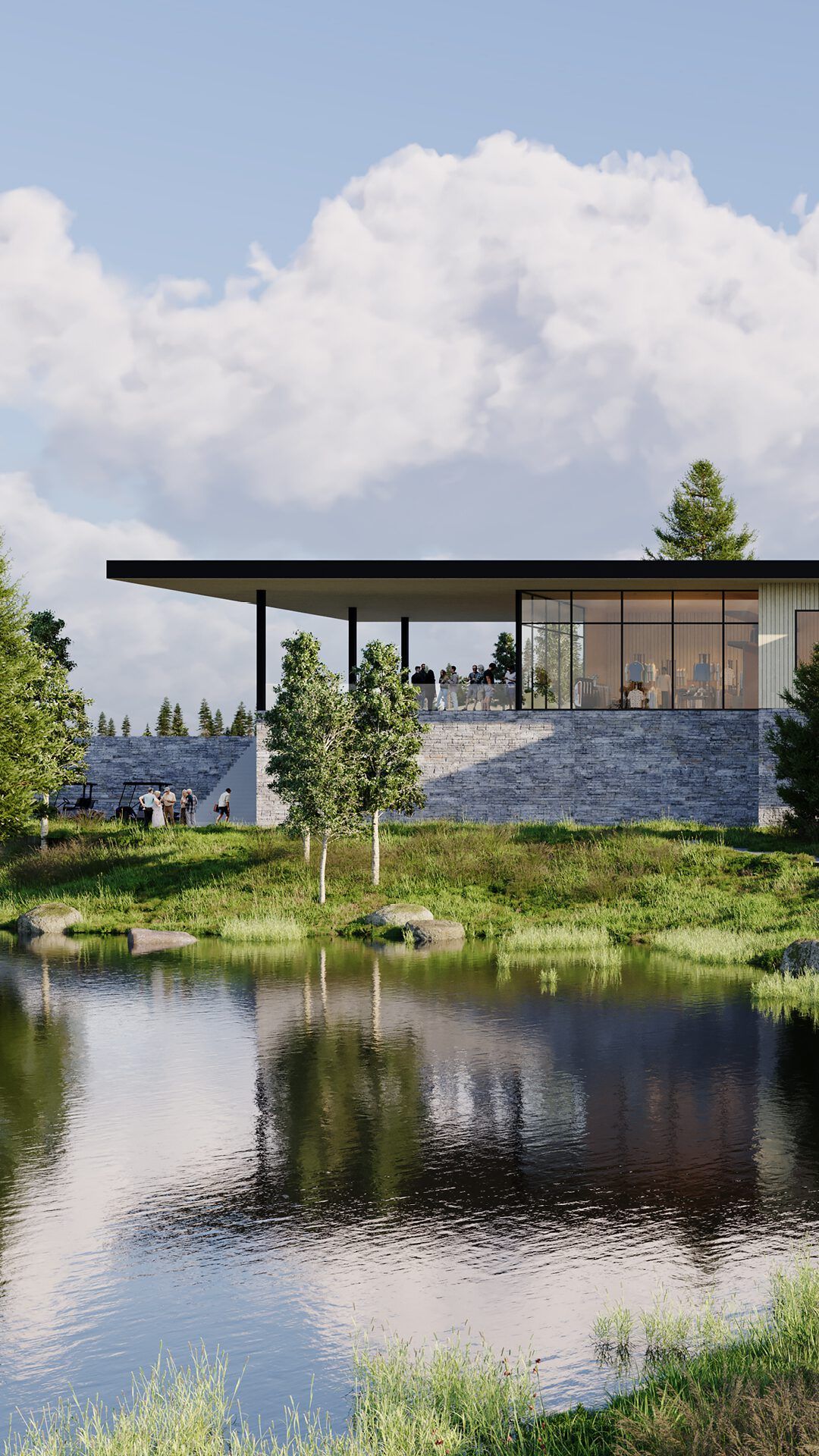 Modern golf clubhouse with stone walls and large glass windows, featuring people on an outdoor terrace, overlooking a reflective lake with surrounding trees and green grass.