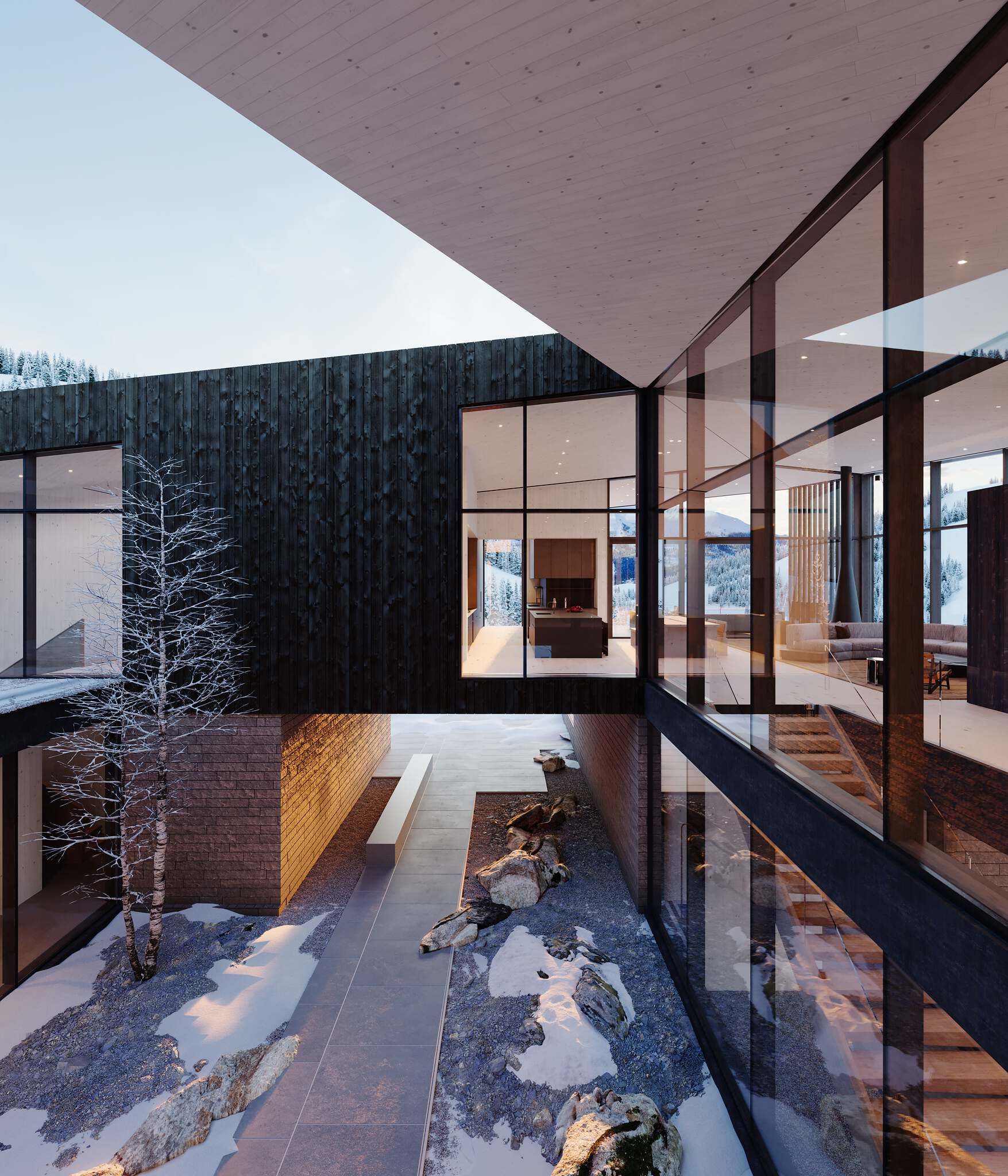 A modern luxury mountain home with extensive glass walls and dark timber cladding in a snowy winter landscape. An open-air courtyard with bare trees, rocks, and snow is central, while warm interior lights illuminate the kitchen and living spaces against a backdrop of snow-capped peaks.