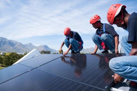 A team of workers install brackets for solar panels on the roof of a house in Cape Town, South Africa
