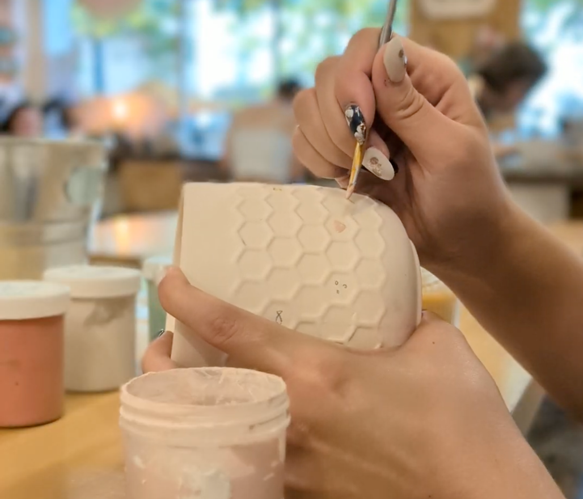 Hands painting on a ceramic mug