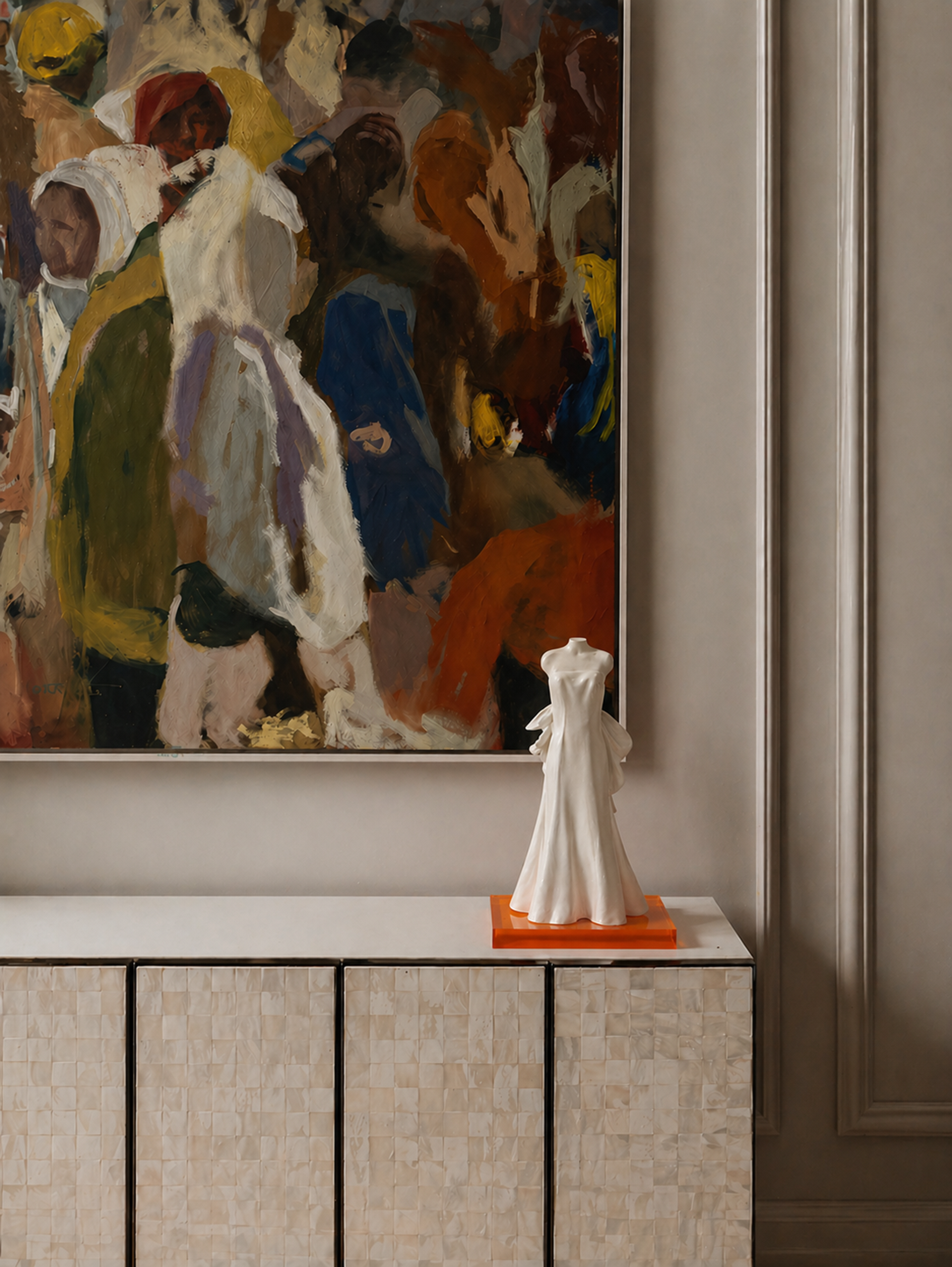 White wedding gown sculpture displayed on a cabinet beneath a framed painting in a residential interior.