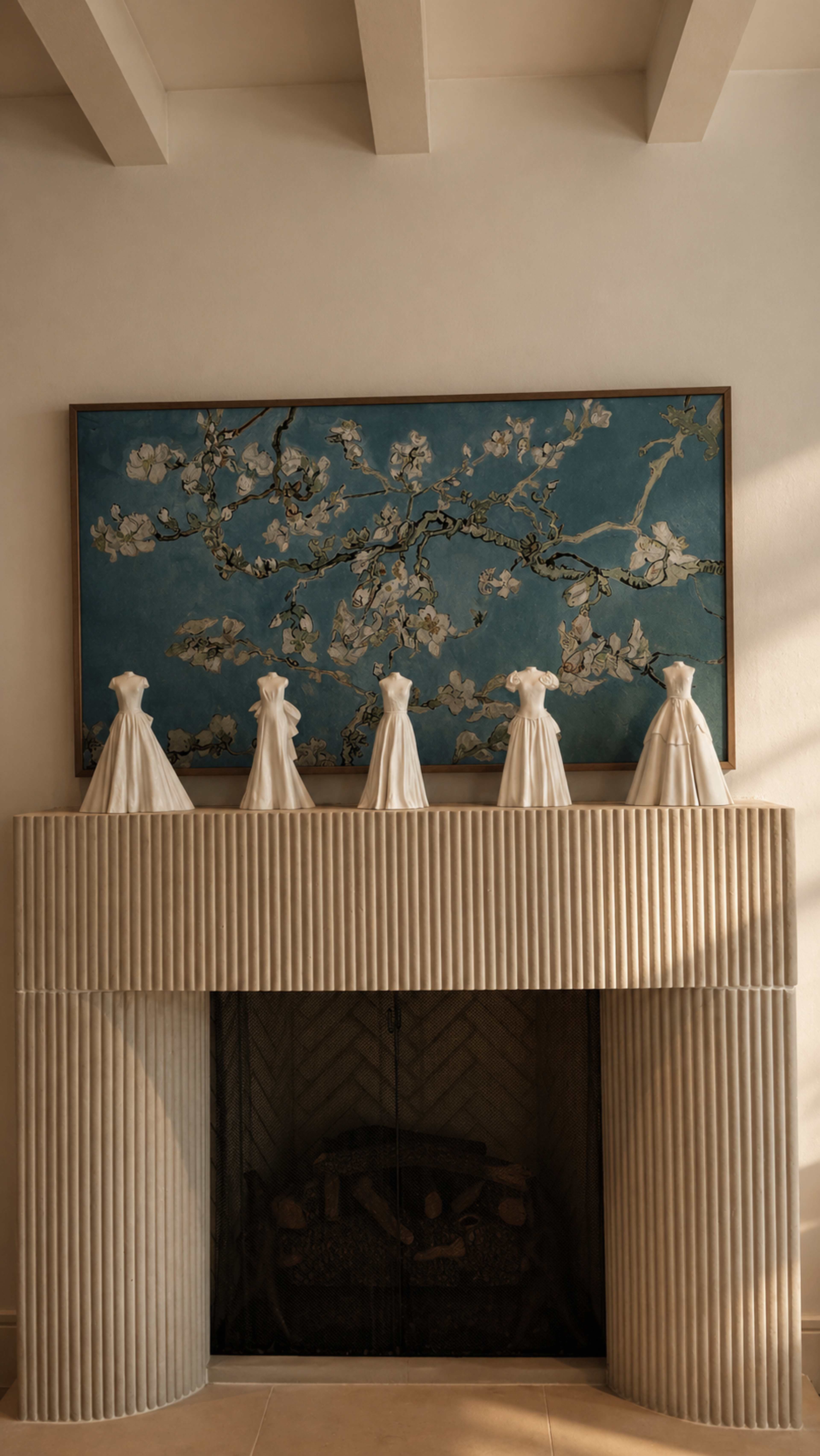 Collection of white wedding gown sculptures displayed on a mantel beneath a framed floral artwork.