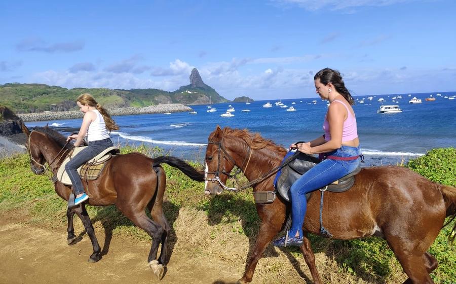 Cavalier sur un sentier de Fernando de Noronha pendant la balade à cheval, avec des dunes en arrière-plan