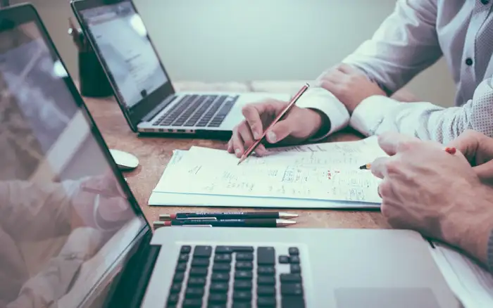 Two advisors reviewing loan figures over laptops and notes