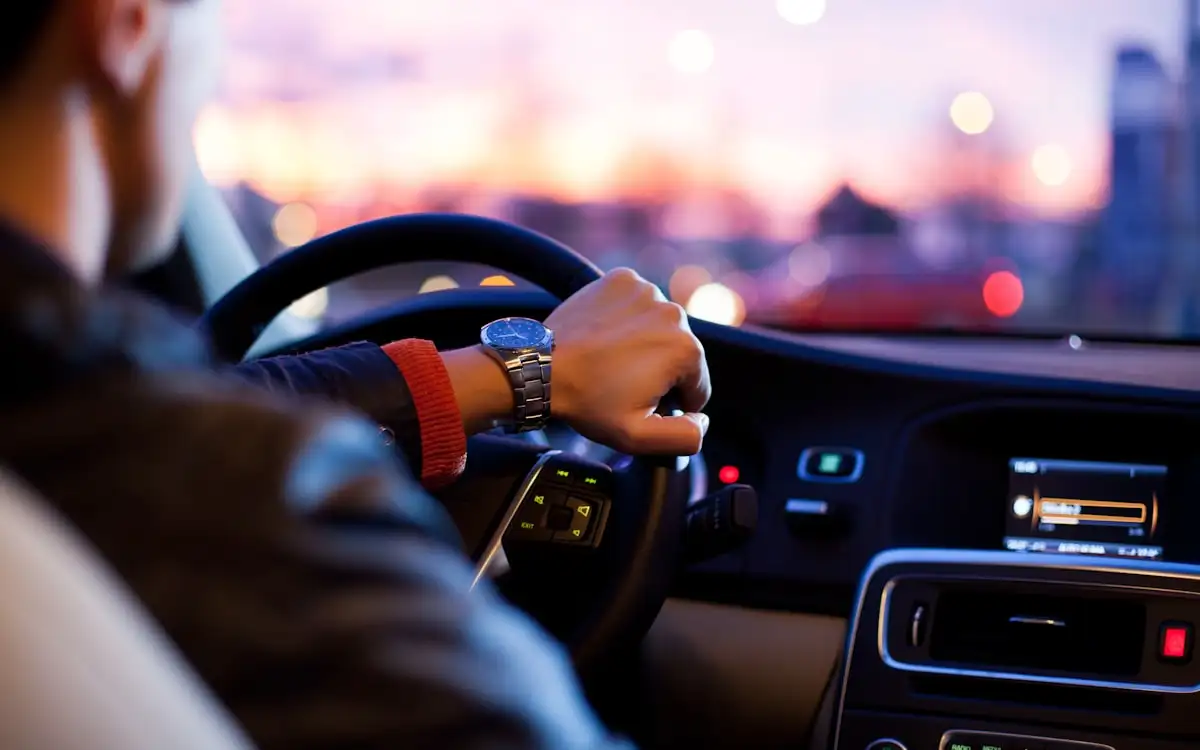 A driver at the wheel watching the dashboard at dusk