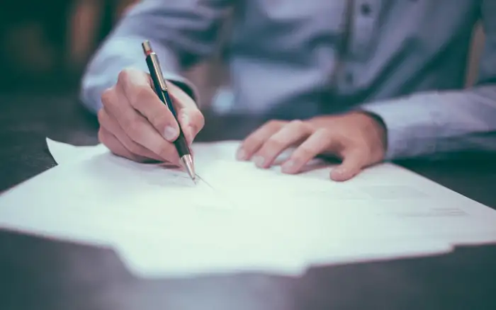 A person signing loan paperwork at a desk