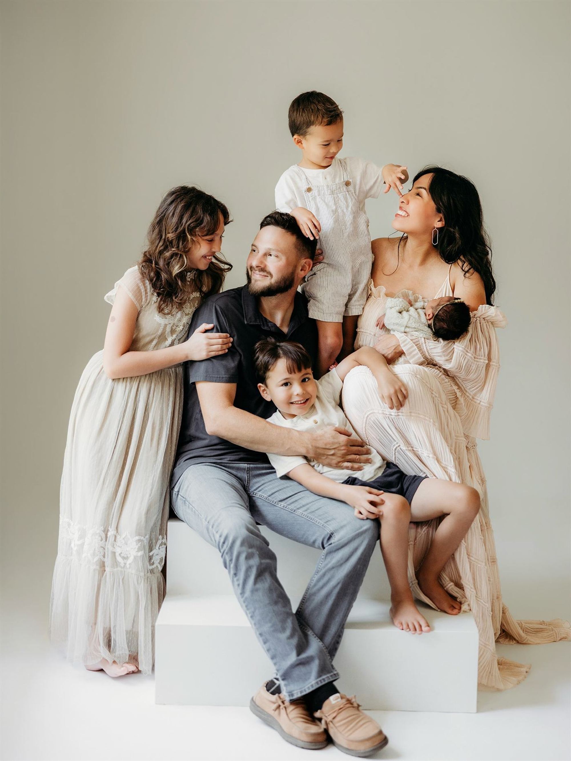 Parents and four children sharing a laugh in a bright studio