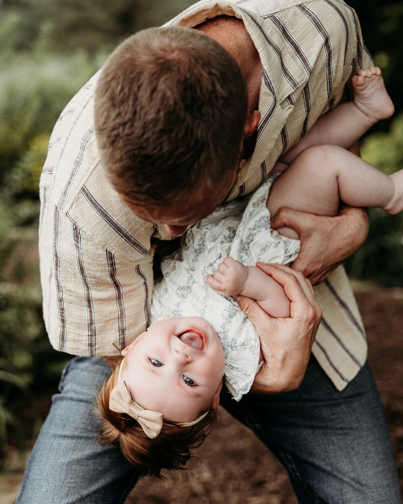 A father playfully holding his giggling daughter upside down