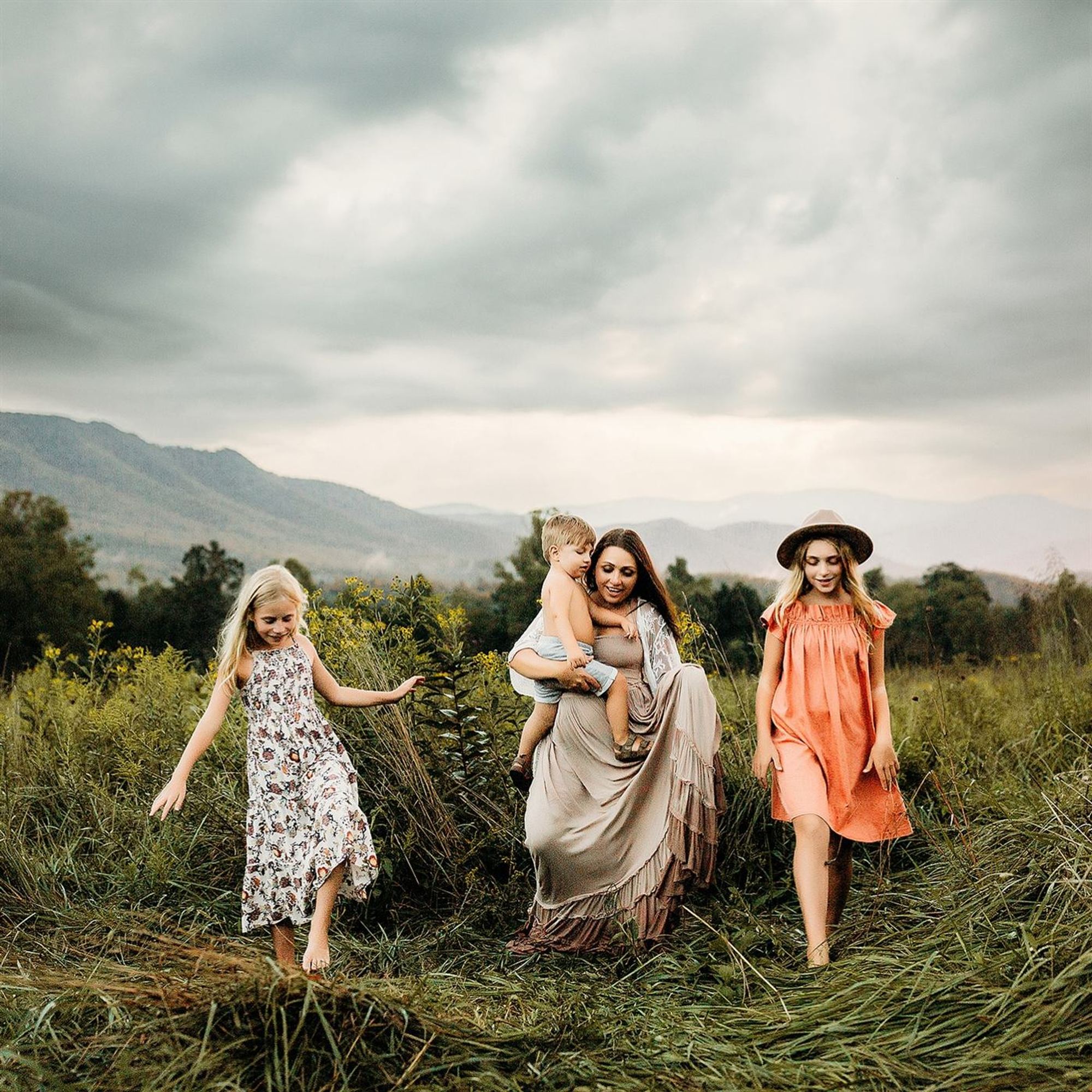 A family walking through tall grass beneath Ozark hills