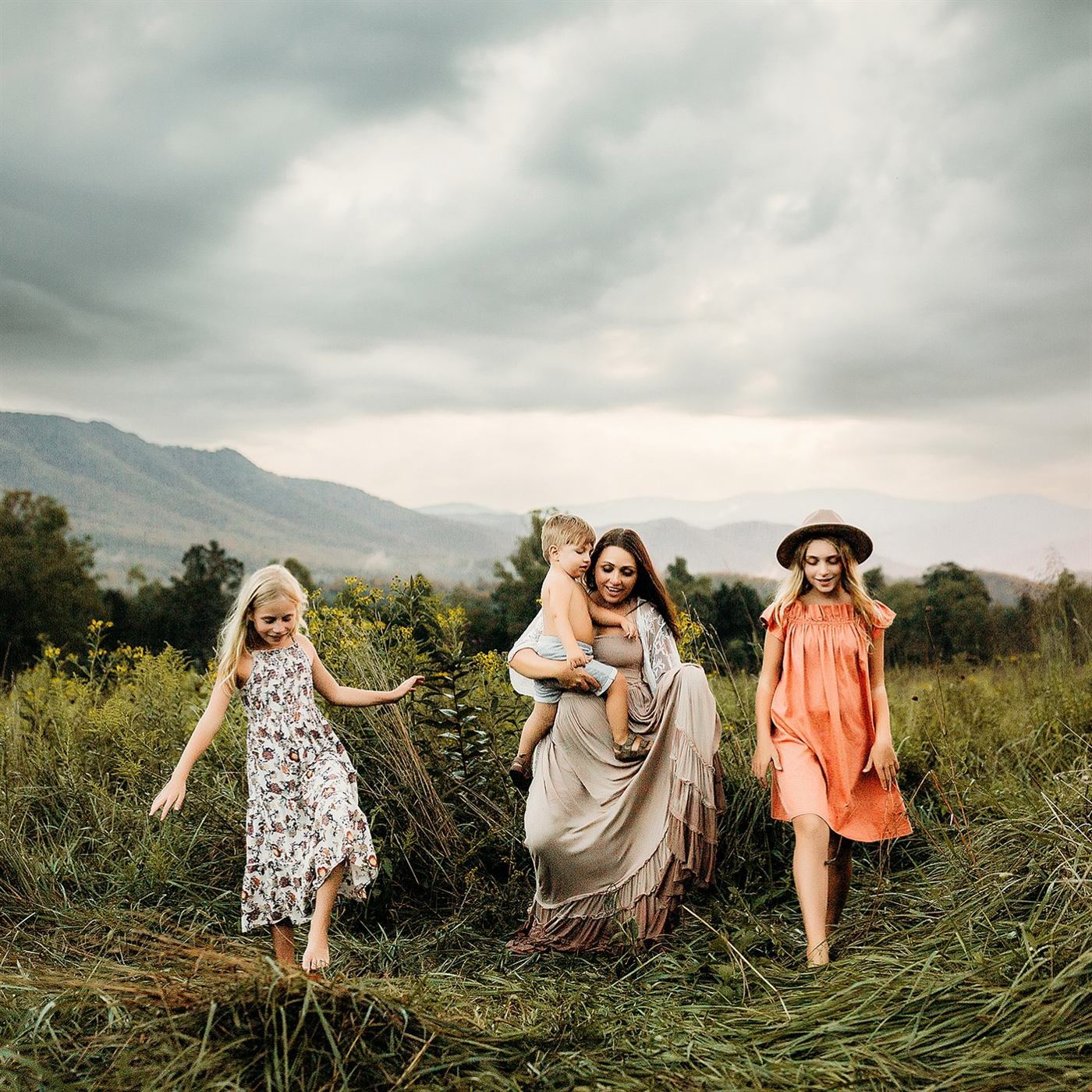 A family walking through tall grass beneath Ozark hills