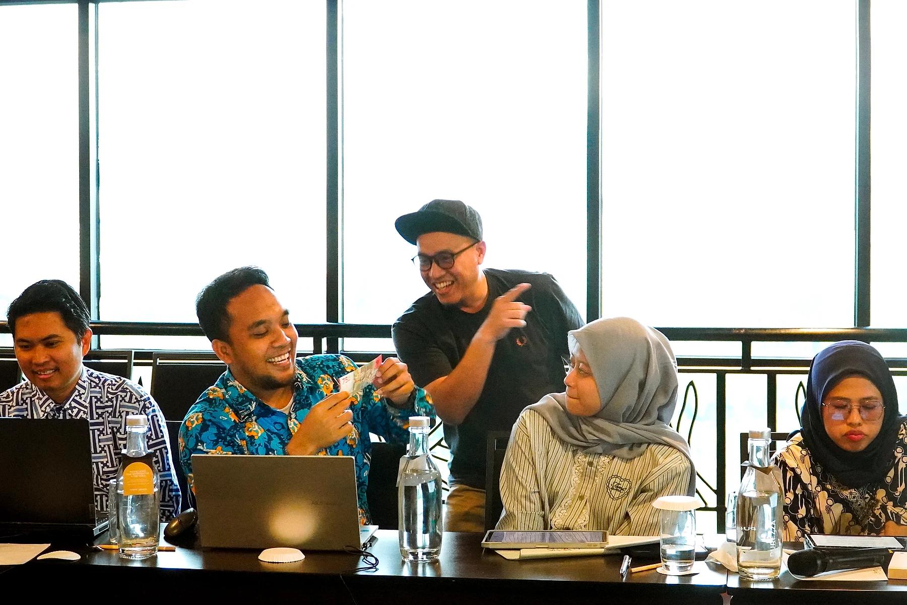 Coach Yoso Lukito berdiskusi santai dengan peserta yang bekerja di depan laptop di ruang rapat