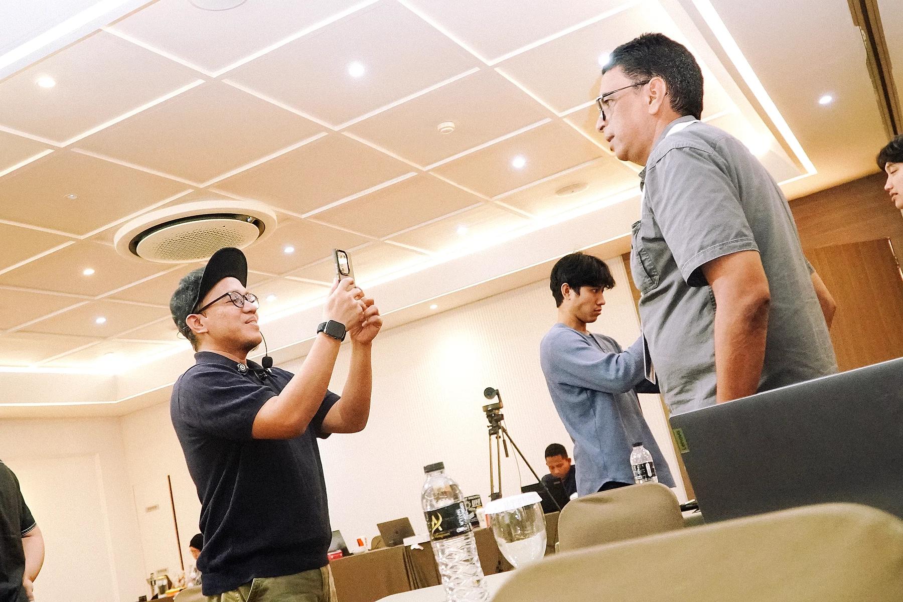 Coach Yoso Lukito memegang HP untuk memotret peserta saat sesi praktik pelatihan digital marketing