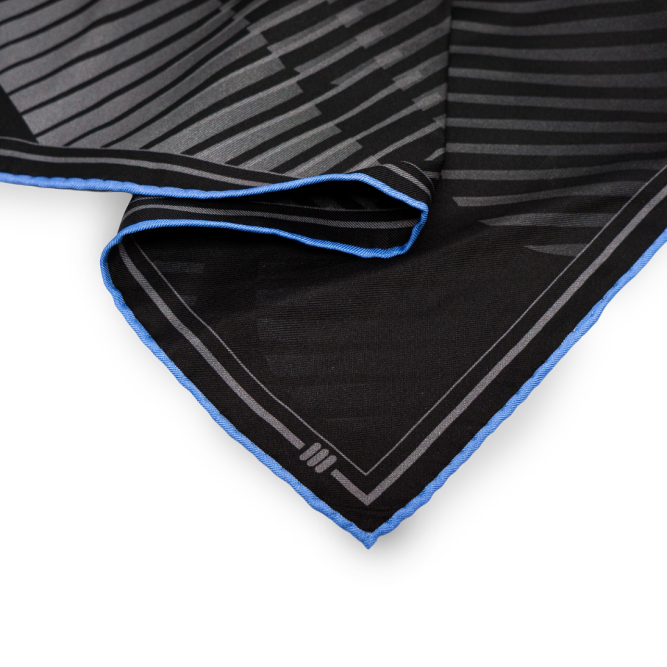 Corner detail of the Signature Abstract scarf — diagonal stripe pattern meeting the cobalt blue hand-rolled edge