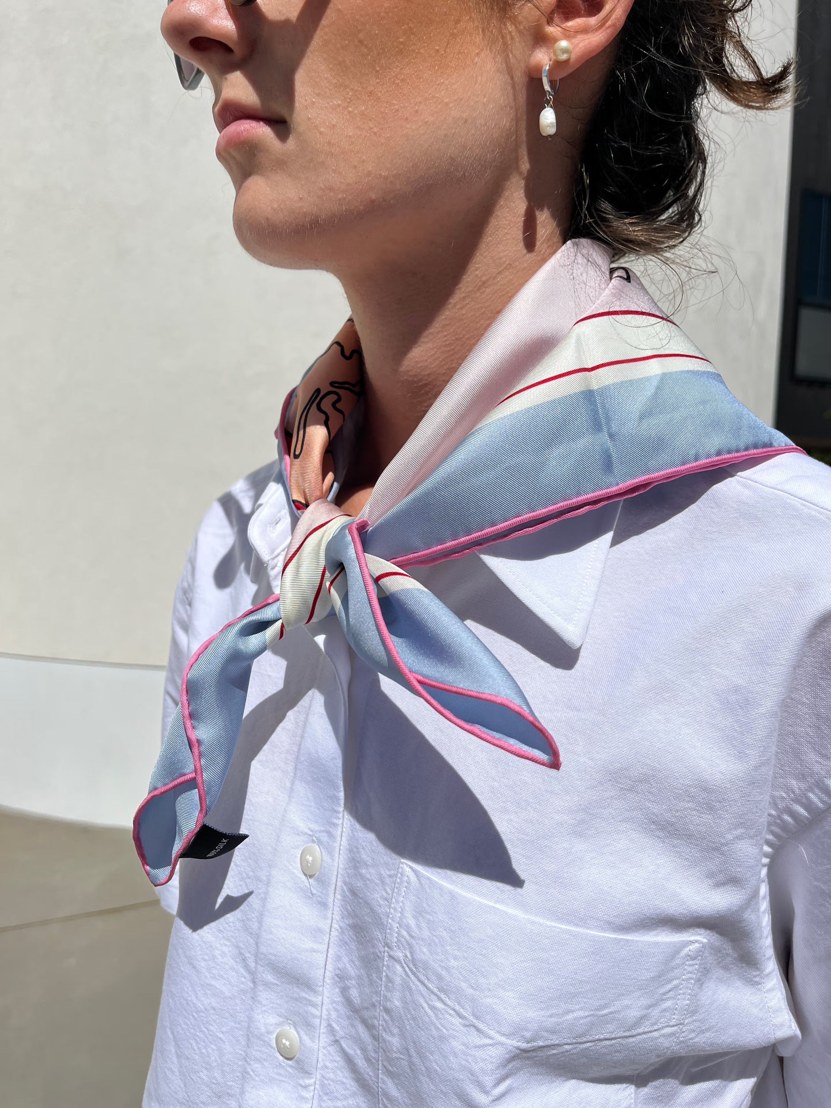 The American Dream silk scarf worn loosely at the neck over a white shirt