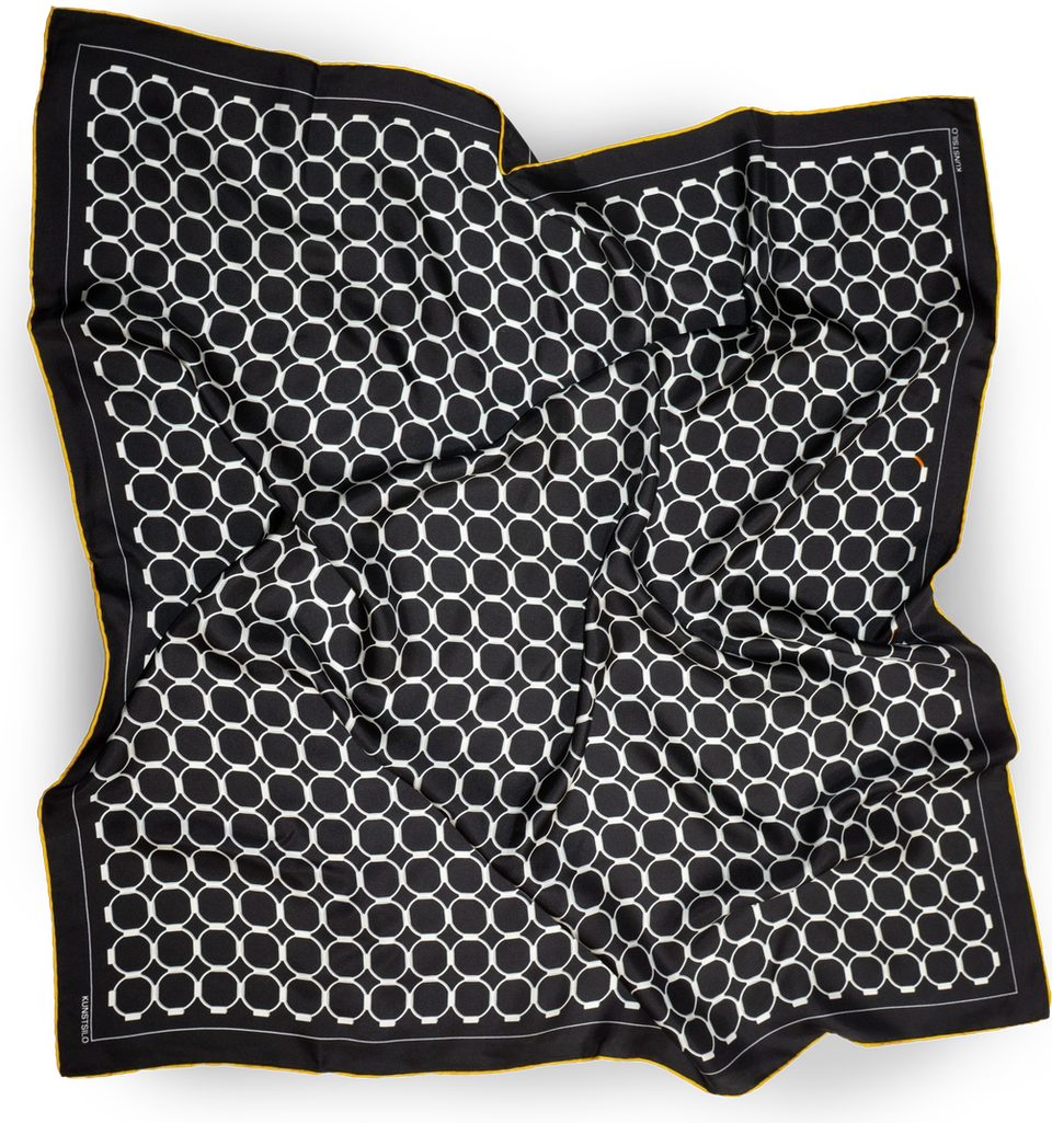 The Signature scarf in black, fully draped — white concentric ring motif across the ground, yellow border