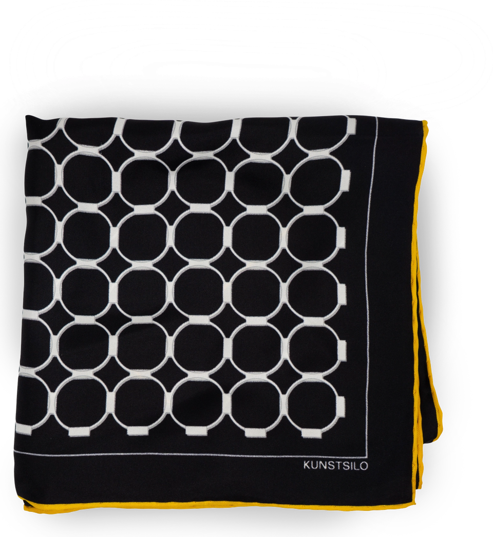 The Signature scarf in black, folded flat — a grid of white rings on black silk, yellow border