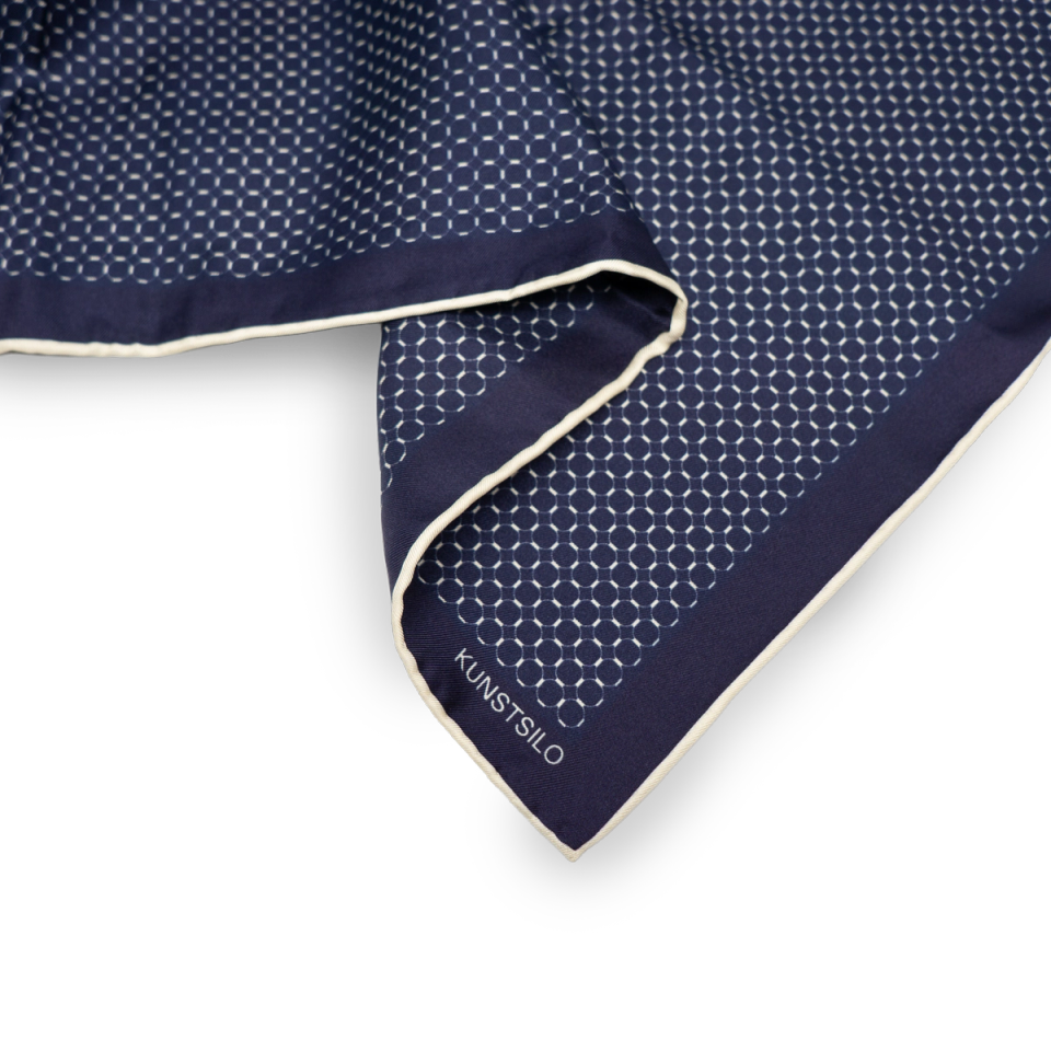 Corner detail of the Signature Bandana — the fine dot-pattern face with "KUNSTSILO" label and cream rolled edge