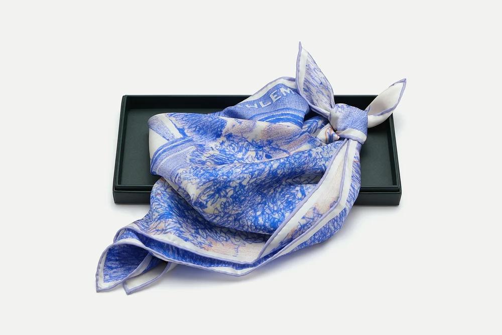 AHLEM Atelier Scarf laid flat on grey — the full print showing wildflowers, climbing plants and small animals across the silk