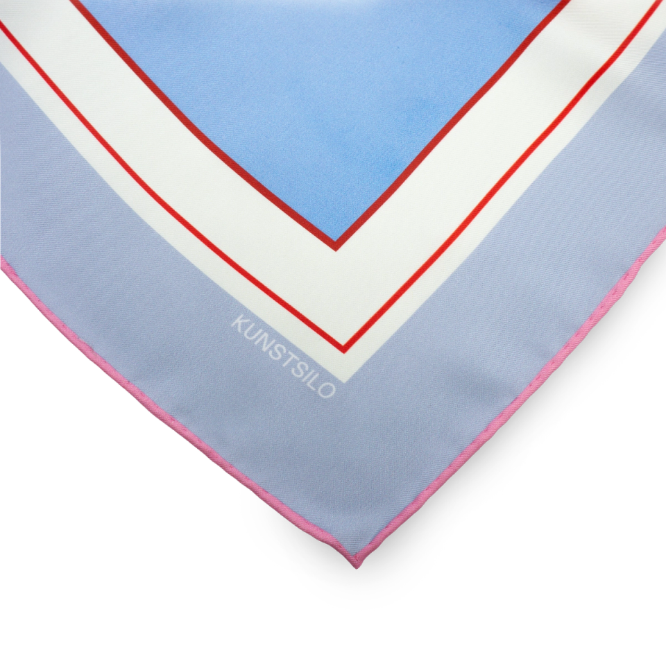 Corner detail of The American Dream silk scarf — the "KUNSTSILO" label and hand-rolled edge on a pale blue ground