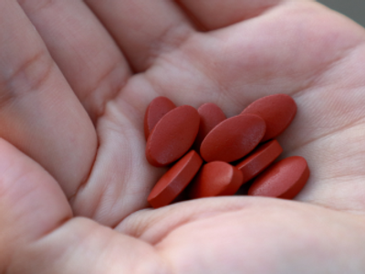 iron supplements with some pills spilling in a person's palm