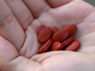 iron supplements with some pills spilling in a person's palm