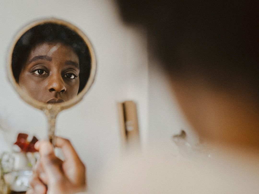 A woman looking into a hand mirror