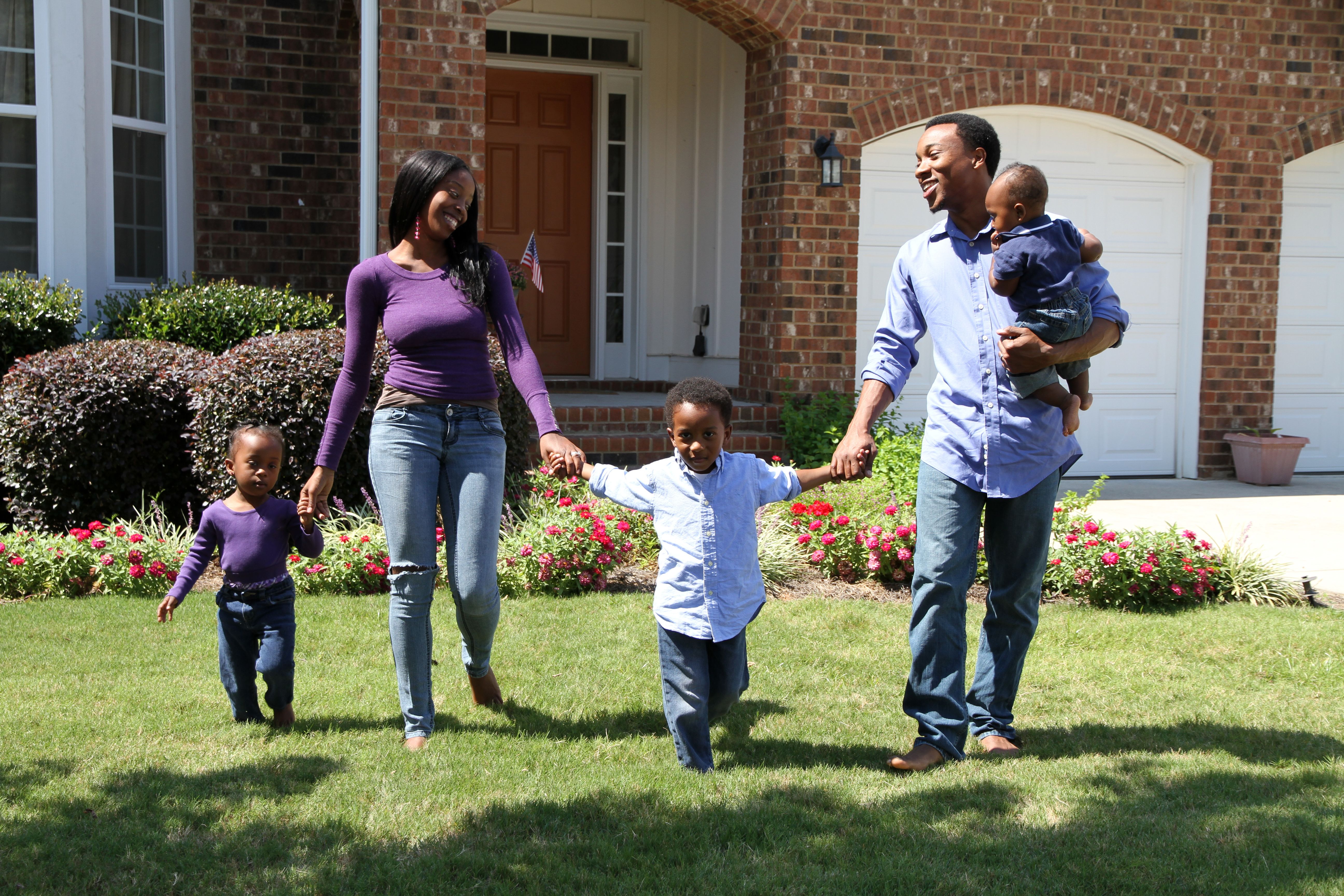 African American family holding hands walking outside 