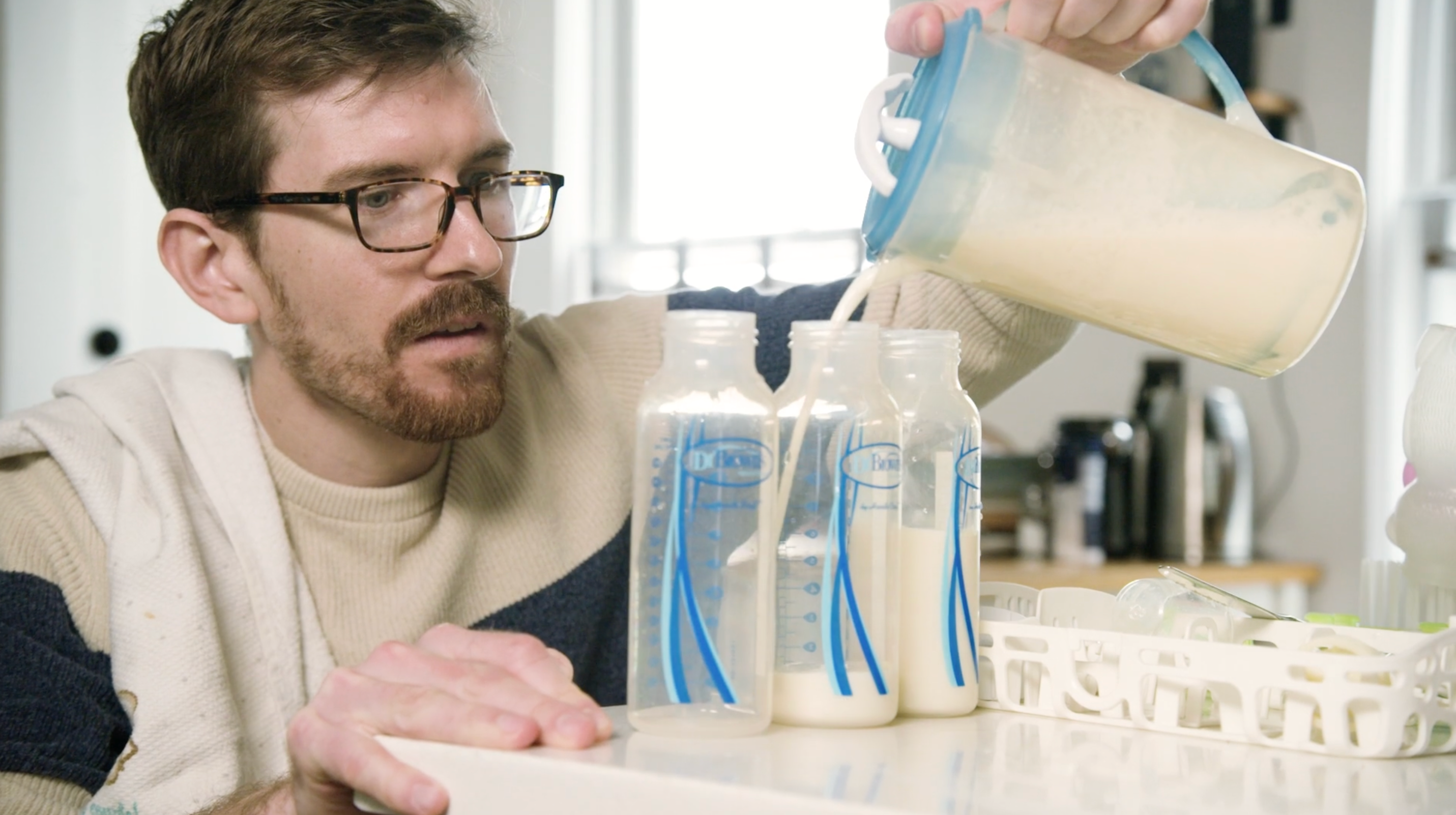 Keegan in his kitchen measuring  and pouring bottles of milks